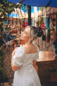 Young woman in a floral dress enjoying a sunny day in an urban setting.